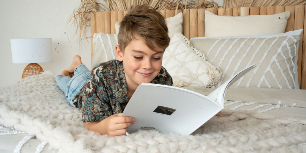 Child reading memory book on bed