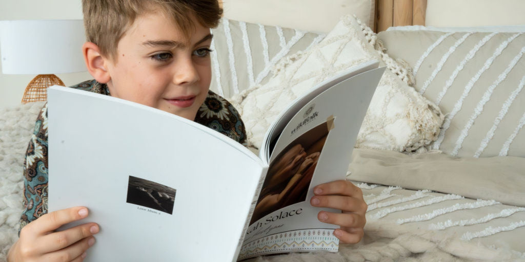 Child reading printed memory book on bed